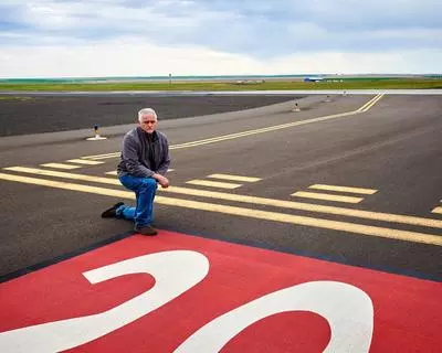 Wayne Green kneels on Runway 11/29 at the Pendleton airport
